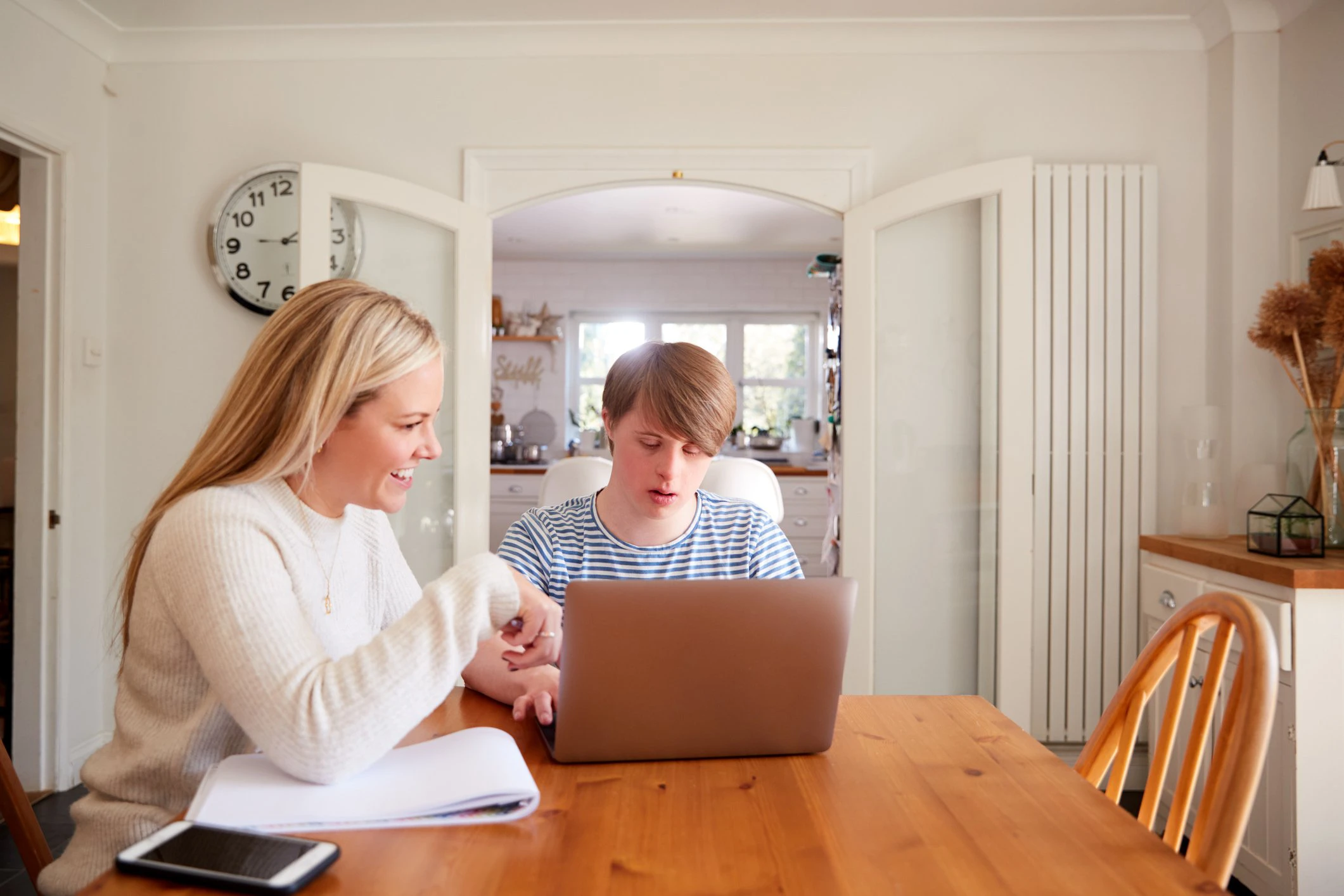 A woman and a teenage boy with Autism learning together on a laptop.