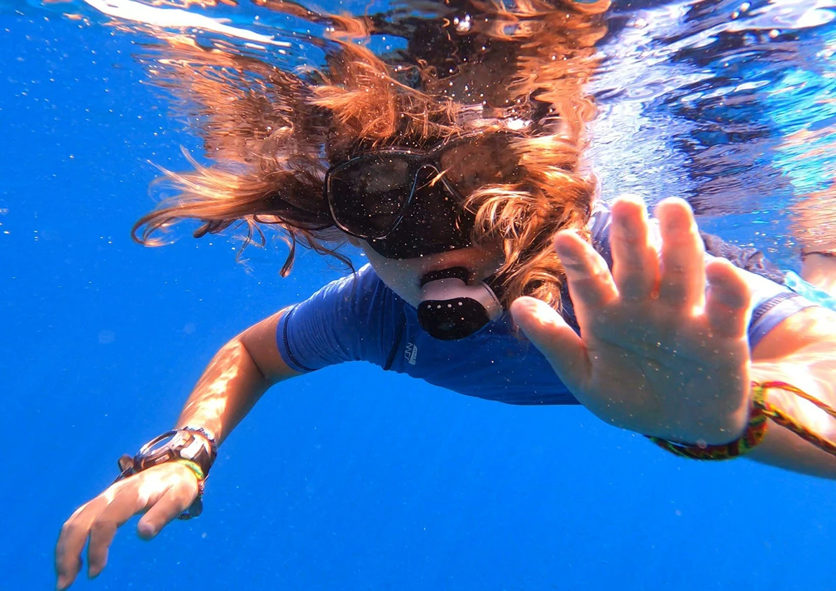 Girl snorkelling in clear blue water.