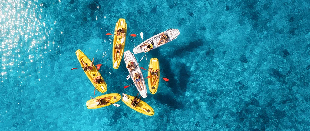 Teenagers kayaking together in the sea during a summer experience.