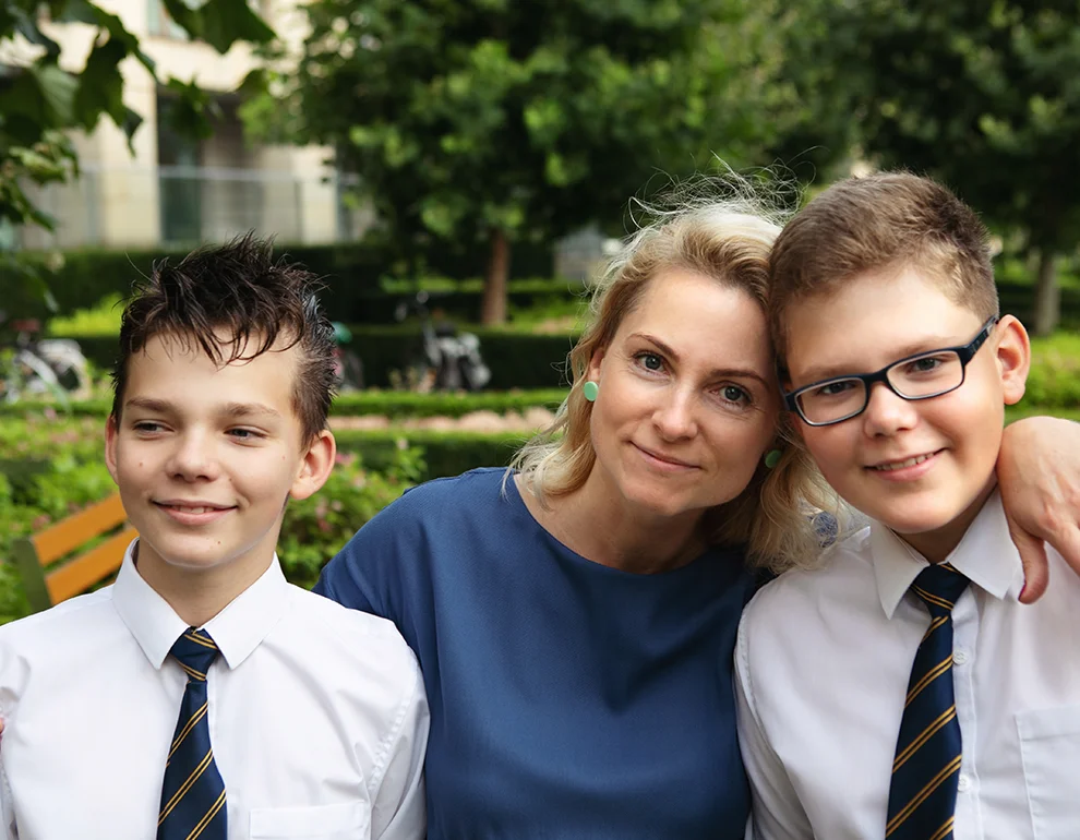 Content mother with her two sons in front of an international school.
